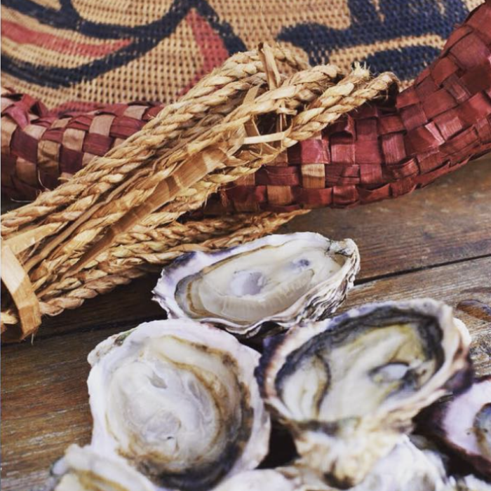 a group of oysters next to a traditional cedar weave hat